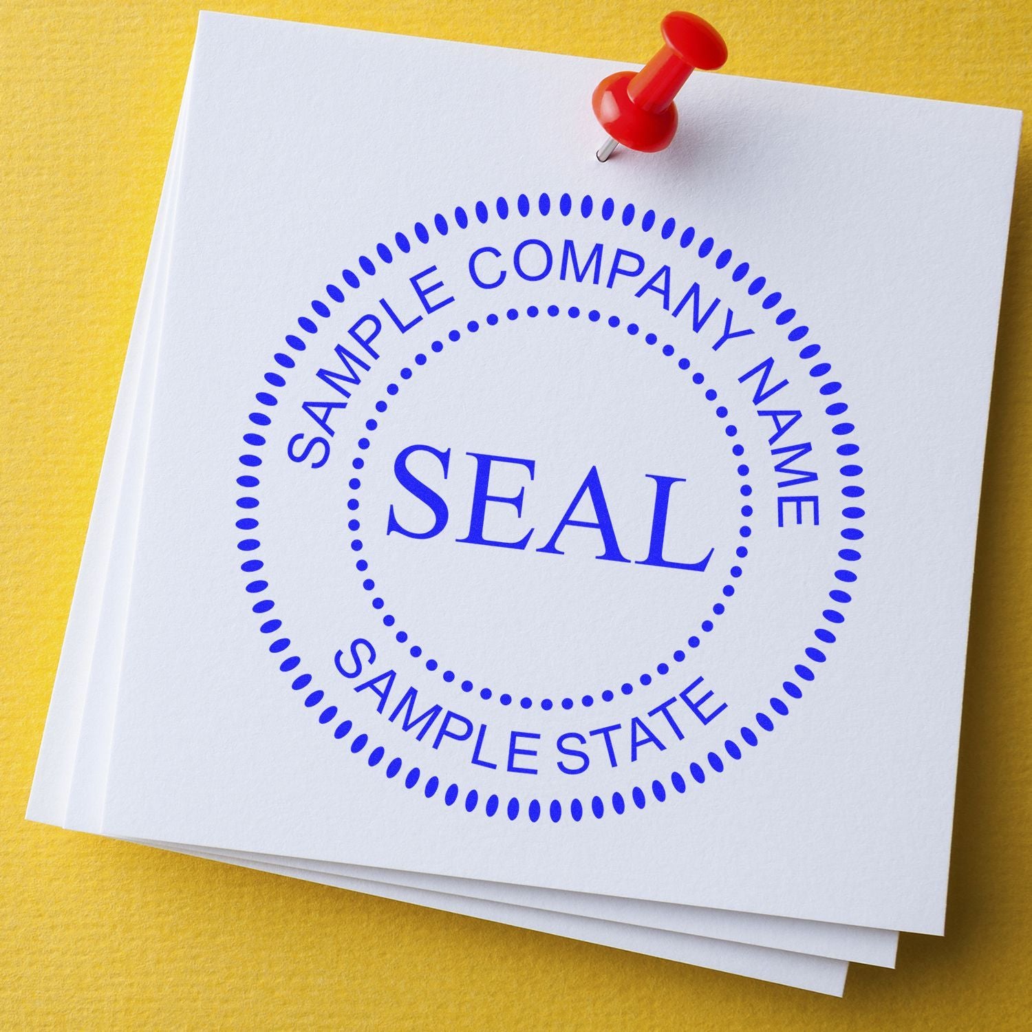Close-up of a sample company name seal stamped on a white document with a red pushpin on yellow background.