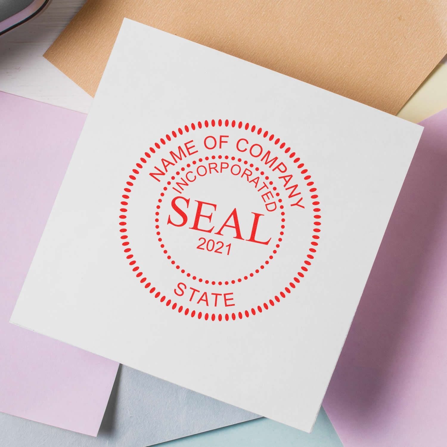 Red company incorporation seal stamp on white paper with pastel envelopes, business document branding concept.