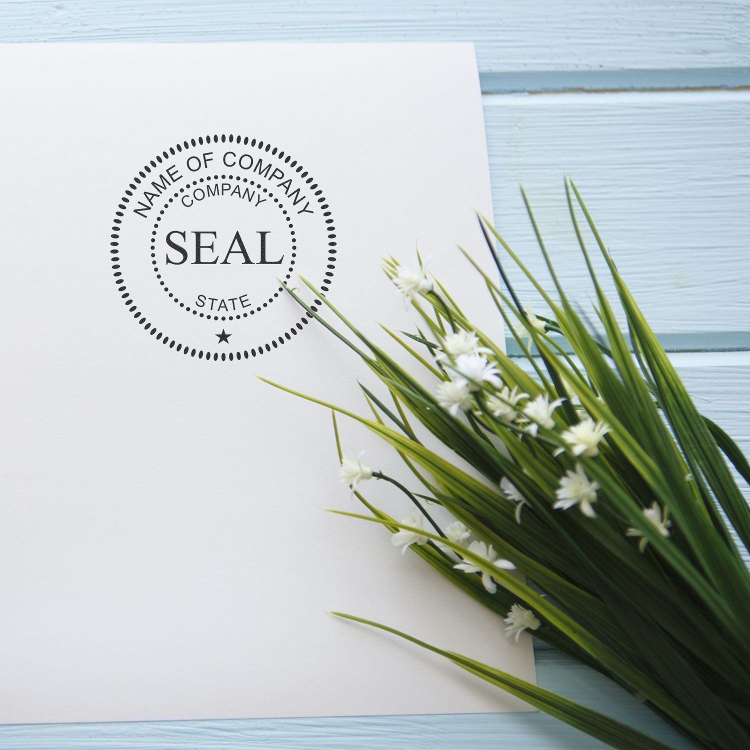 Blank company seal logo mockup on white paper with green floral accents on a blue wooden background.