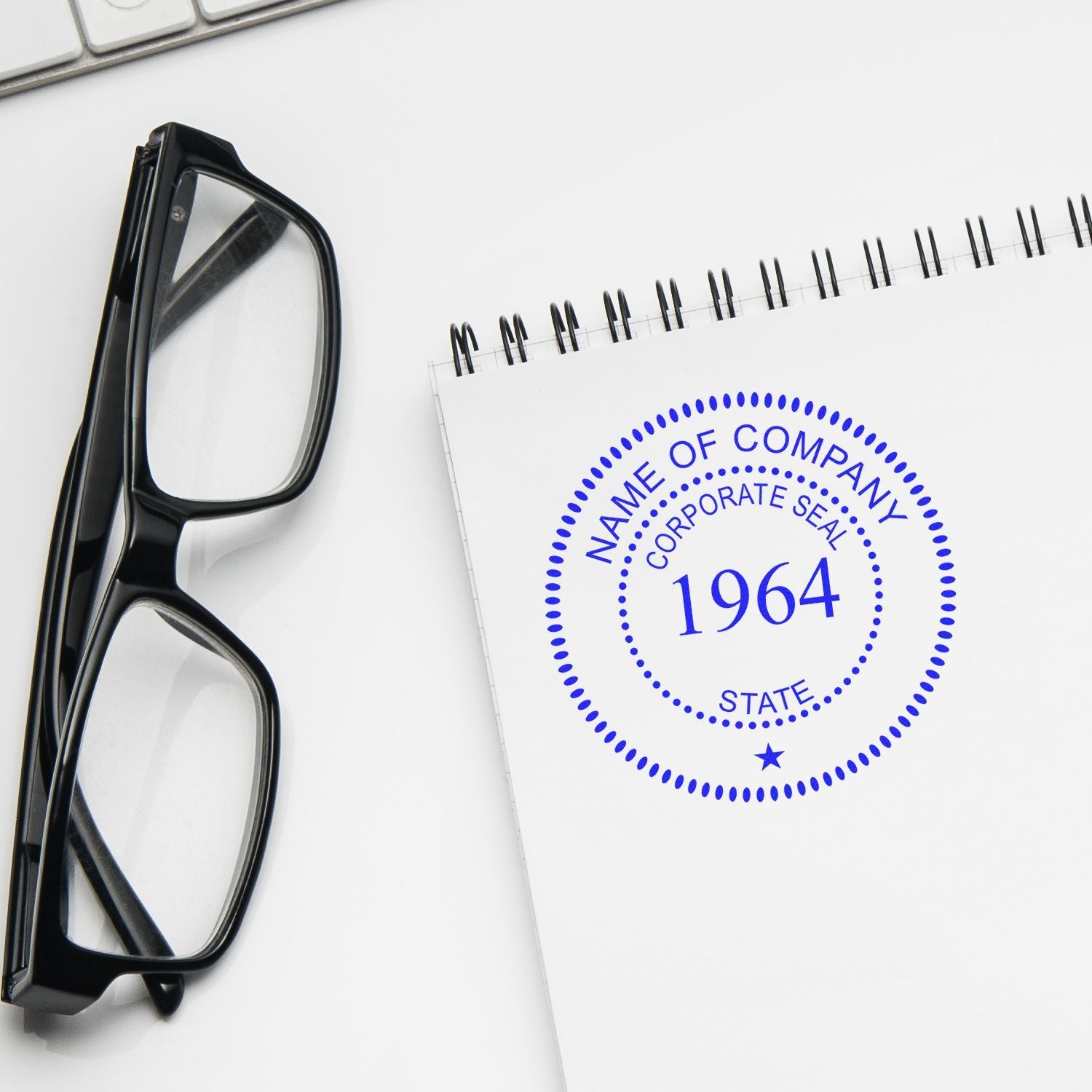 Black eyeglasses beside a notebook with a corporate seal logo and 1964 on a clean white office desk.