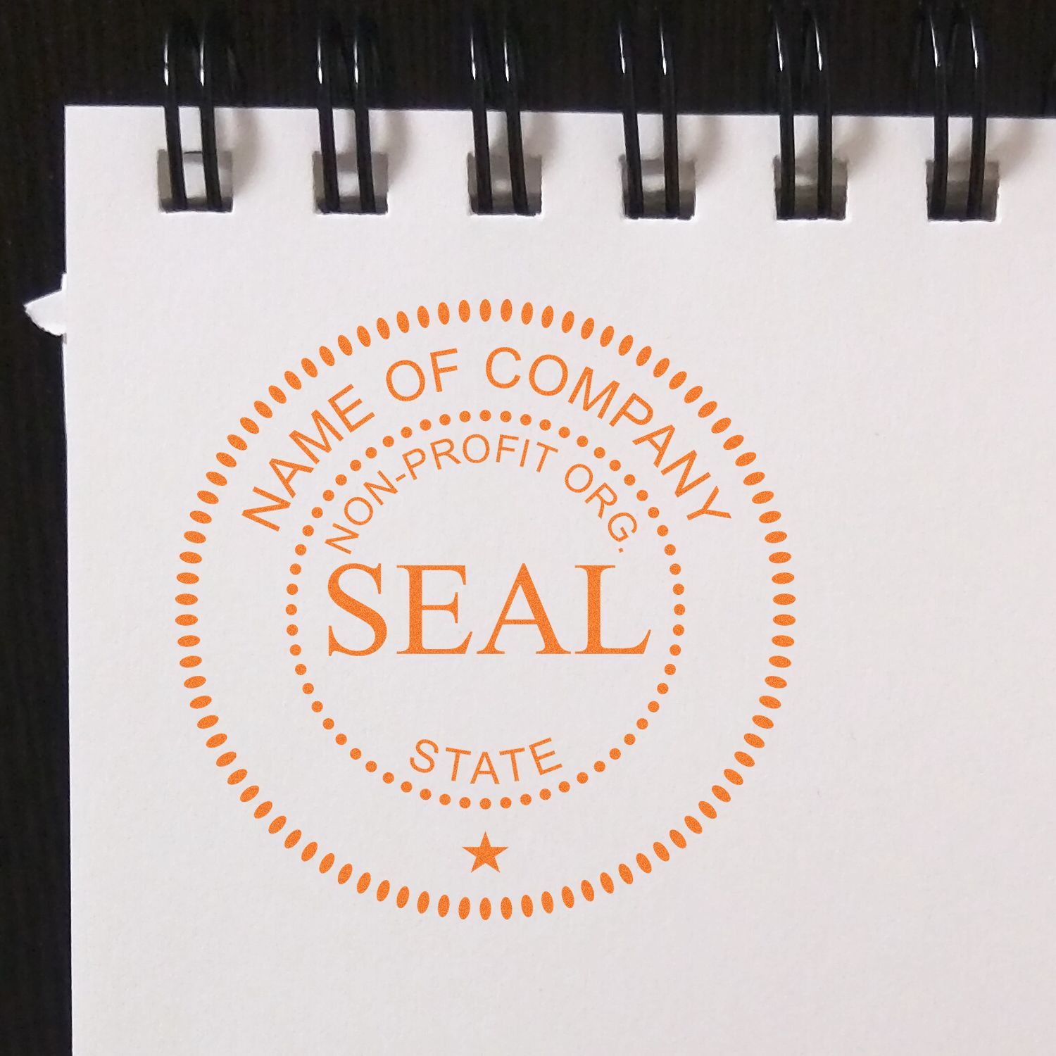 Orange nonprofit organization seal template on a spiral notebook page with Name of Company, Non-Profit Org., and State text.