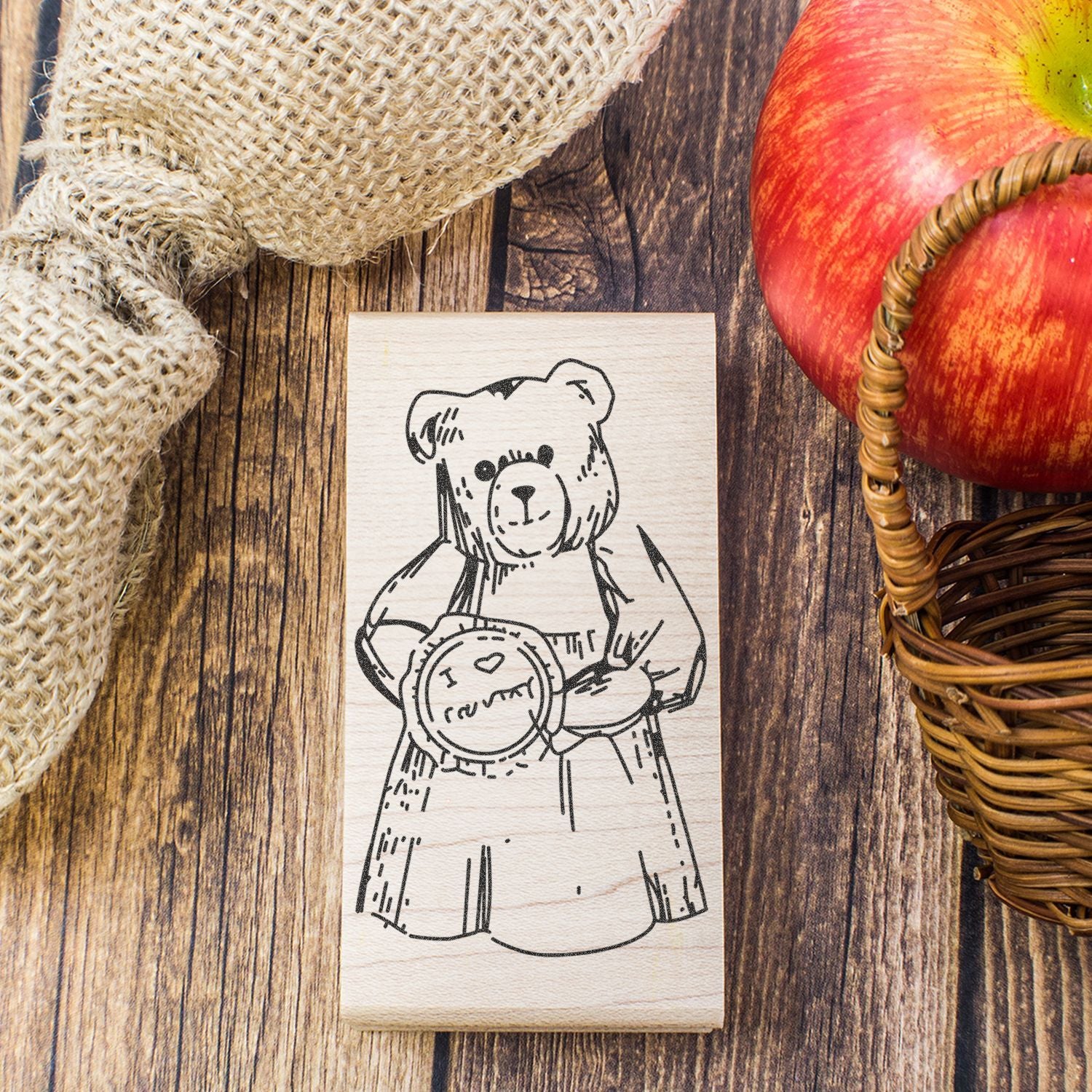 Rustic teddy bear wooden stamp design with heart, styled with burlap and apple basket on a wood background