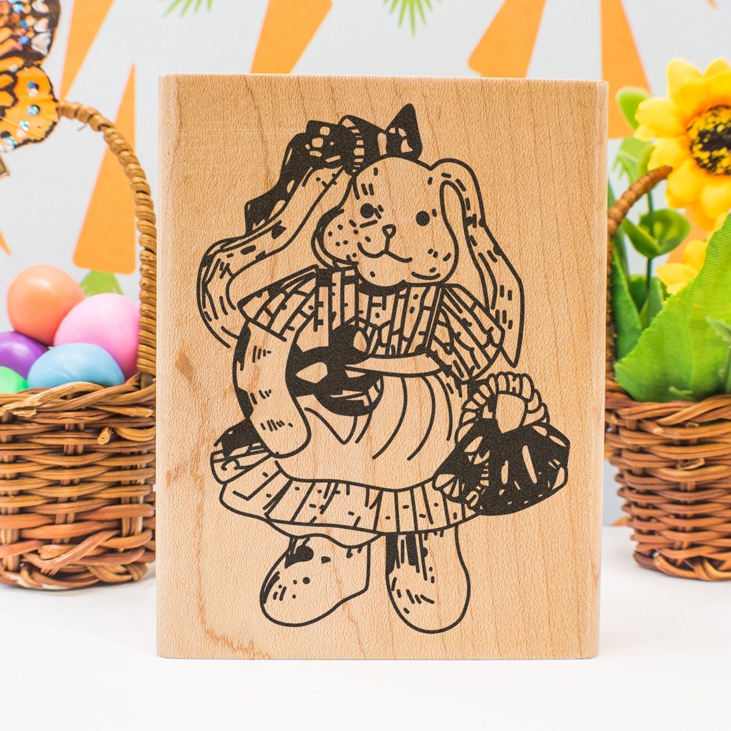 Wooden Easter bunny stamp with floral dress, surrounded by colorful eggs and spring decorations.