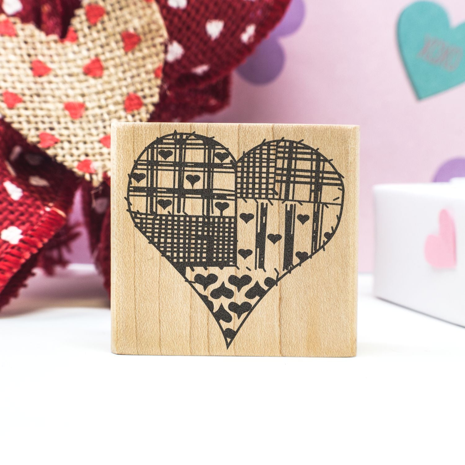 Wooden heart stamp block with decorative love pattern, handmade Valentines Day craft on pink background