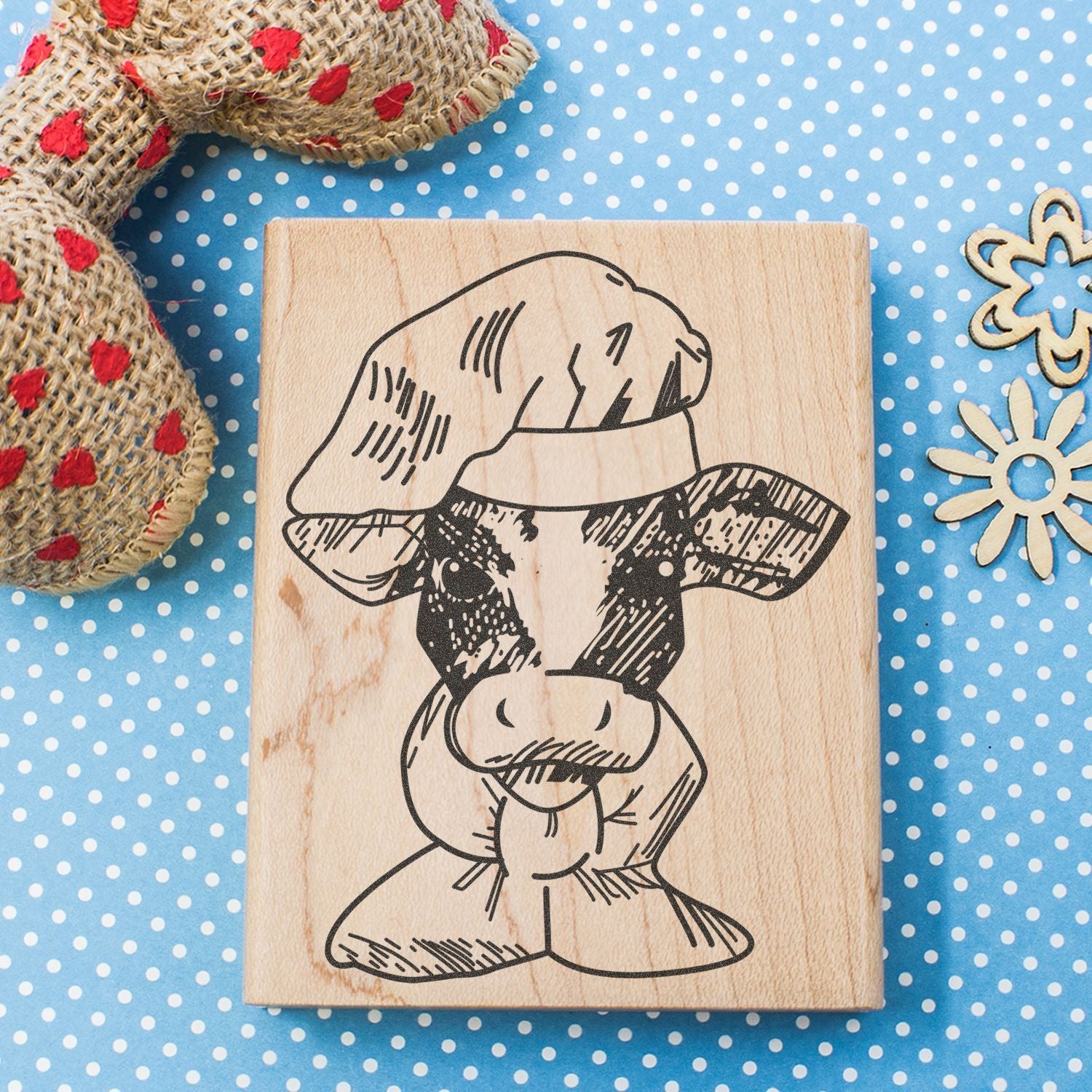 Cow head stamp on wooden block with polka dot background, rustic farmhouse craft decor.