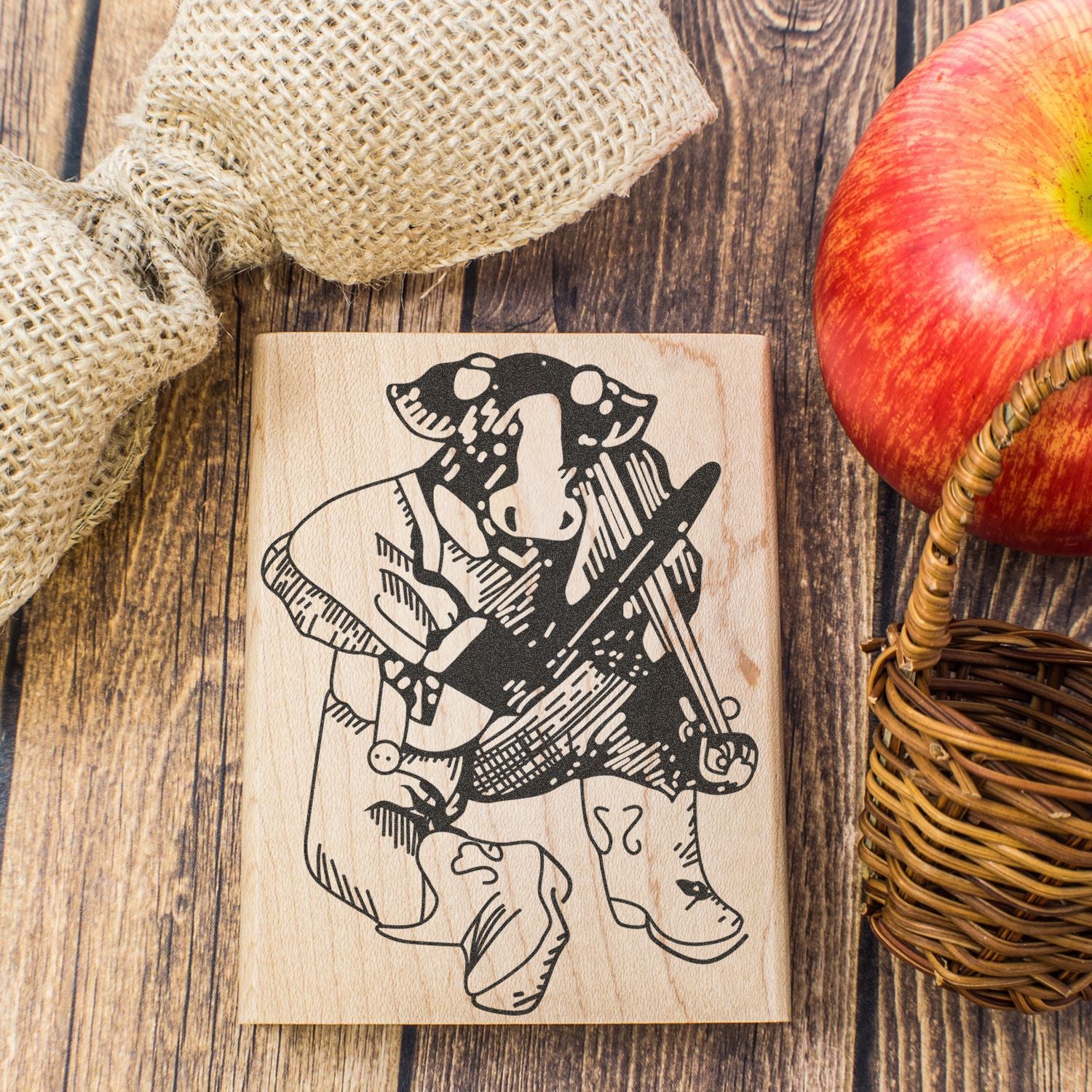 Rustic wooden cow engraved sign with apple and burlap decor on a farmhouse-style wooden table.