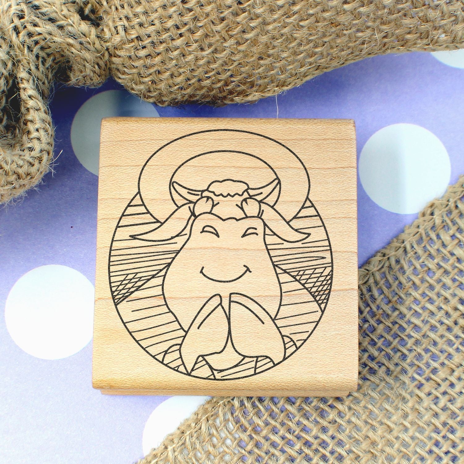 Wooden rubber stamp with cute smiling cow design on a polka dot background.