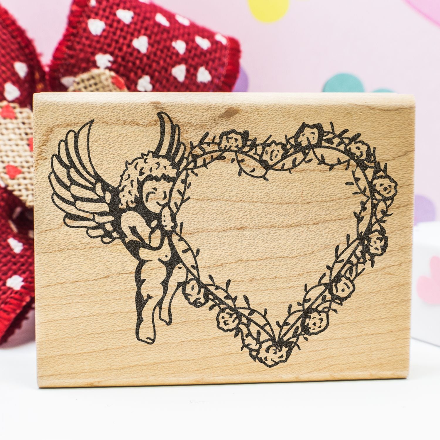 Wooden stamp with engraved angel and floral heart design on a craft background