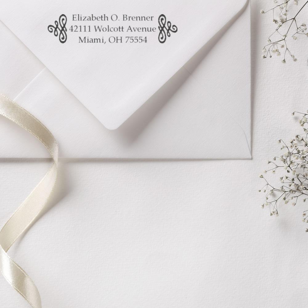 Custom return address rubber stamp on white envelope for wedding invitations, featuring elegant monogram and personalized mailing.