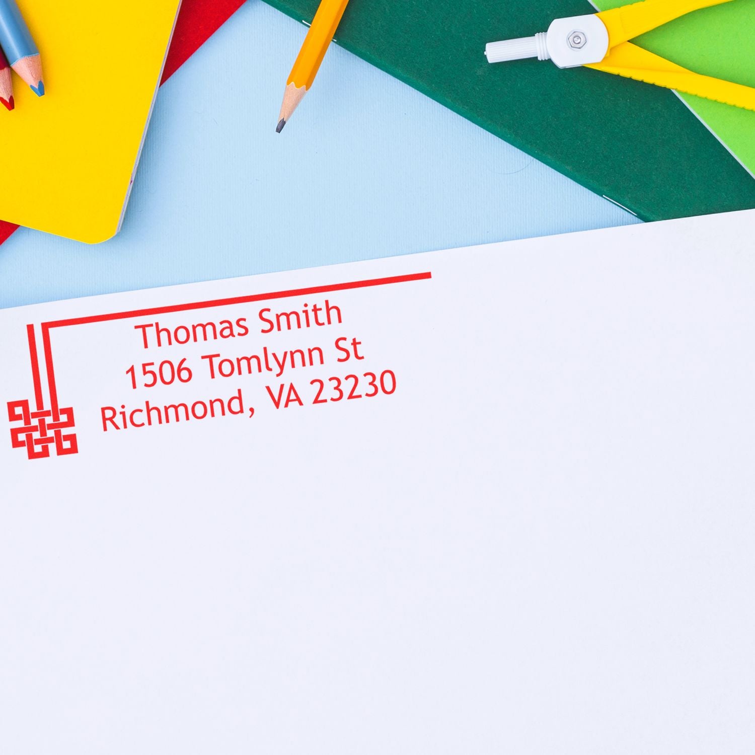 Custom return address rubber stamp on envelope for mailing, featuring name and address with stationery accessories.