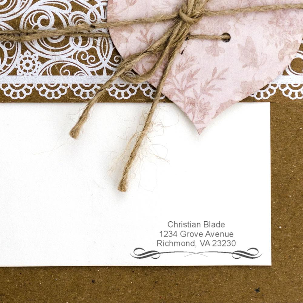Custom return address rubber stamp on rustic wedding invitation envelope with lace and twine.