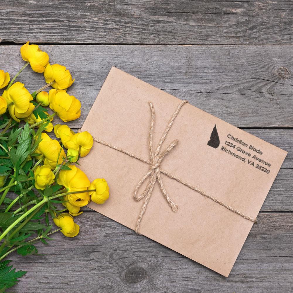 Custom return address rubber stamp on kraft envelope tied with twine, ideal for branded wedding invitations and gift packaging.