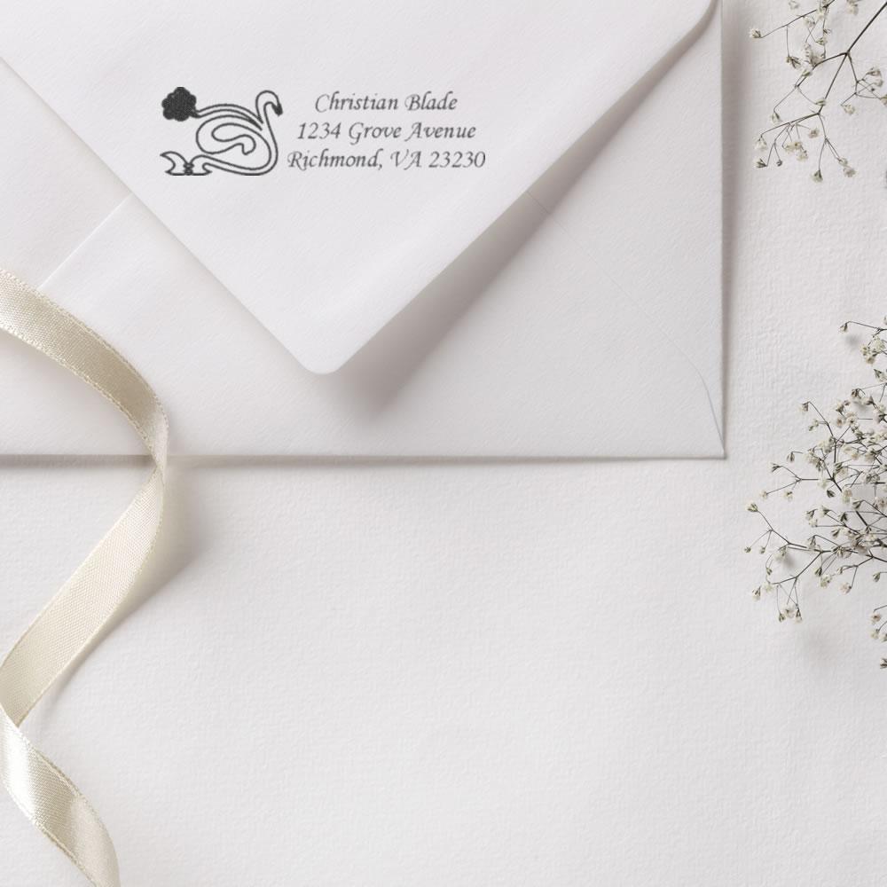 Custom return address rubber stamp on a wedding invitation envelope with elegant swan design.