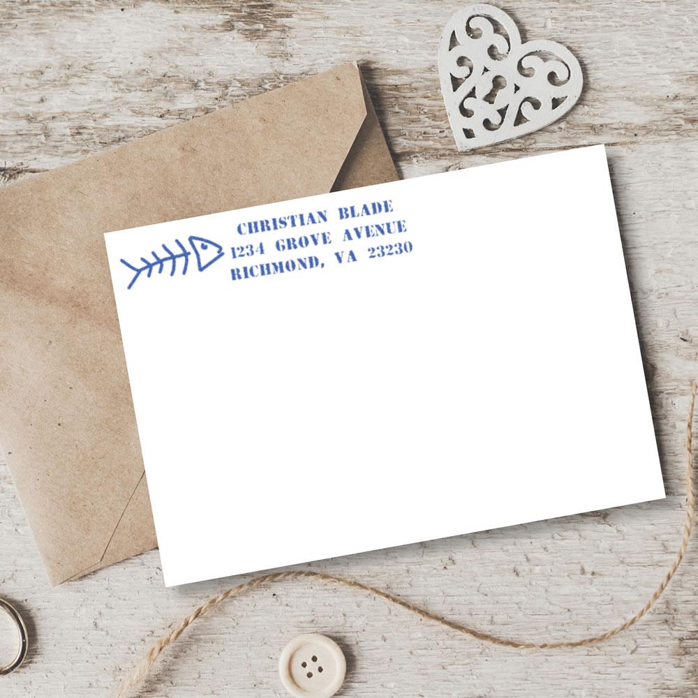 Custom return address rubber stamp on a white envelope with blue fishbone design for personalized mailing and stationery.