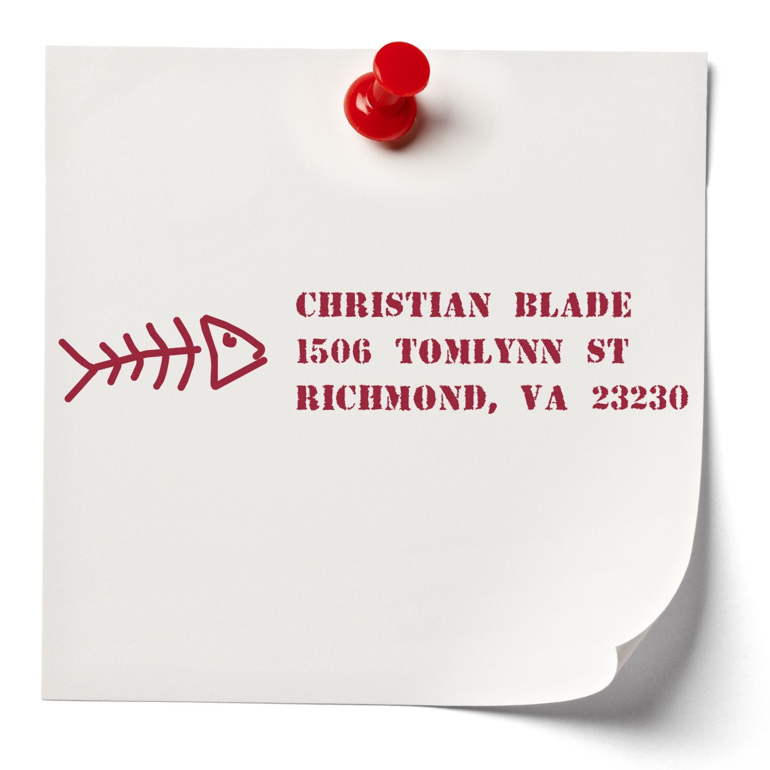 Custom return address rubber stamp with fish bone logo and red ink on paper, pinned with a red push pin.