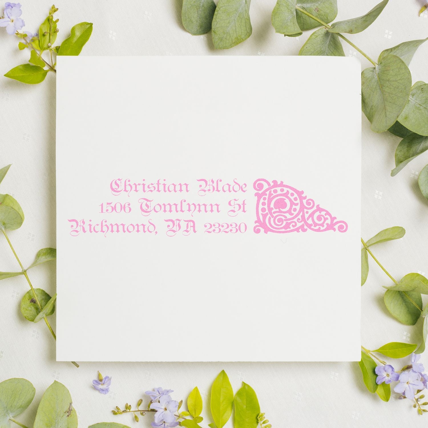 Pink custom return address rubber stamp with ornate monogram on white envelope, ideal for personalized wedding stationery.
