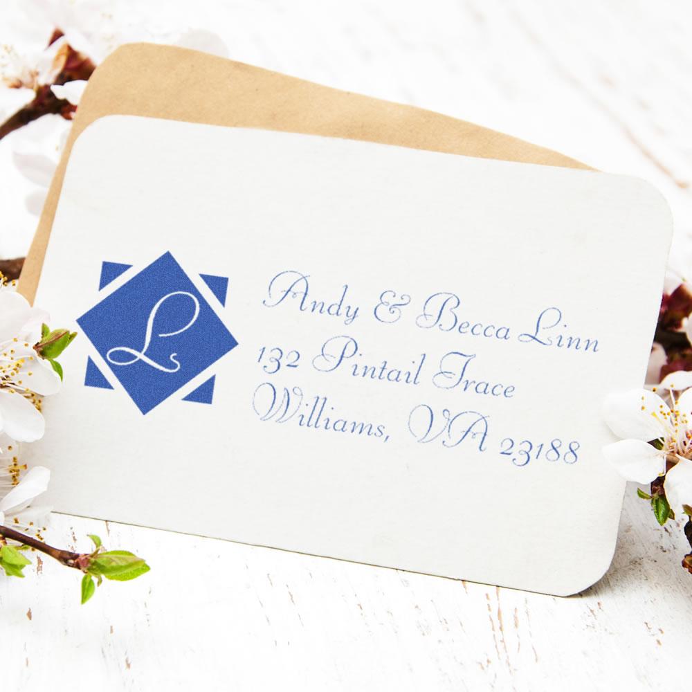 Personalized return address rubber stamp with monogram L and blue script address on envelope.