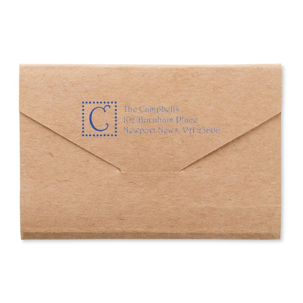 Personalized return address rubber stamp on a kraft envelope with monogram and blue ink.