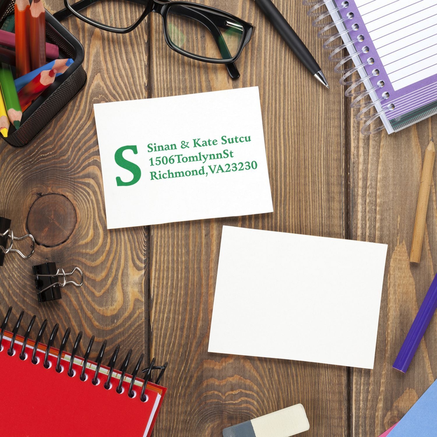 Custom return address rubber stamp on blank stationery, featuring green name and address imprint for personalized mailings.