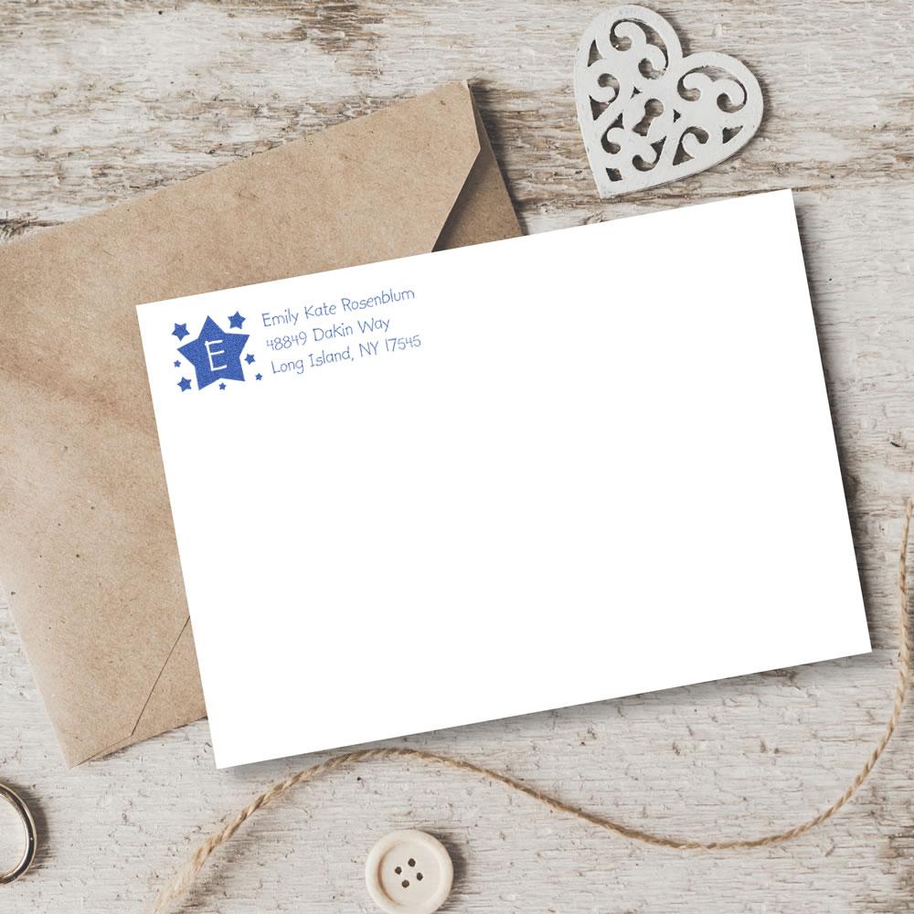 Custom address rubber stamp with star monogram on envelope and stationery for personalized mailing.