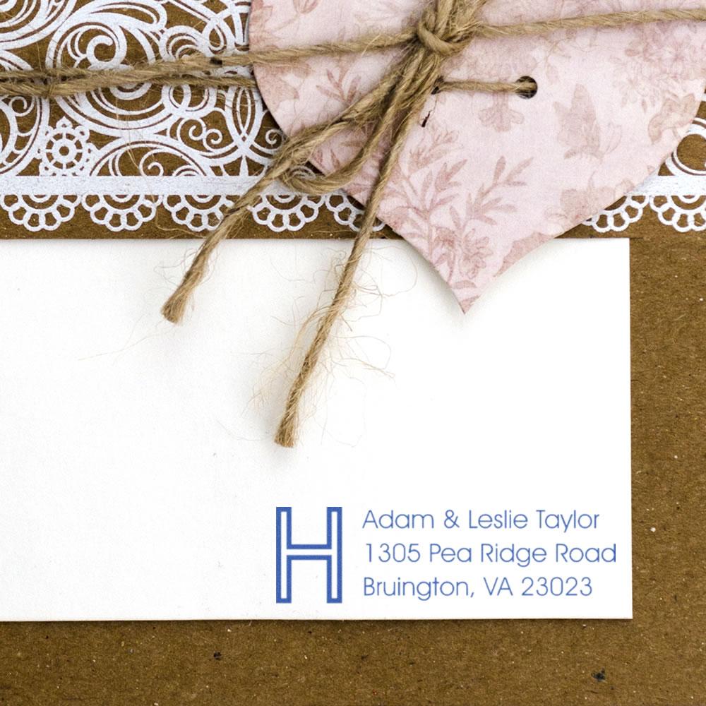 Custom return address rubber stamp with monogram H for Adam and Leslie Taylor on a wedding envelope.