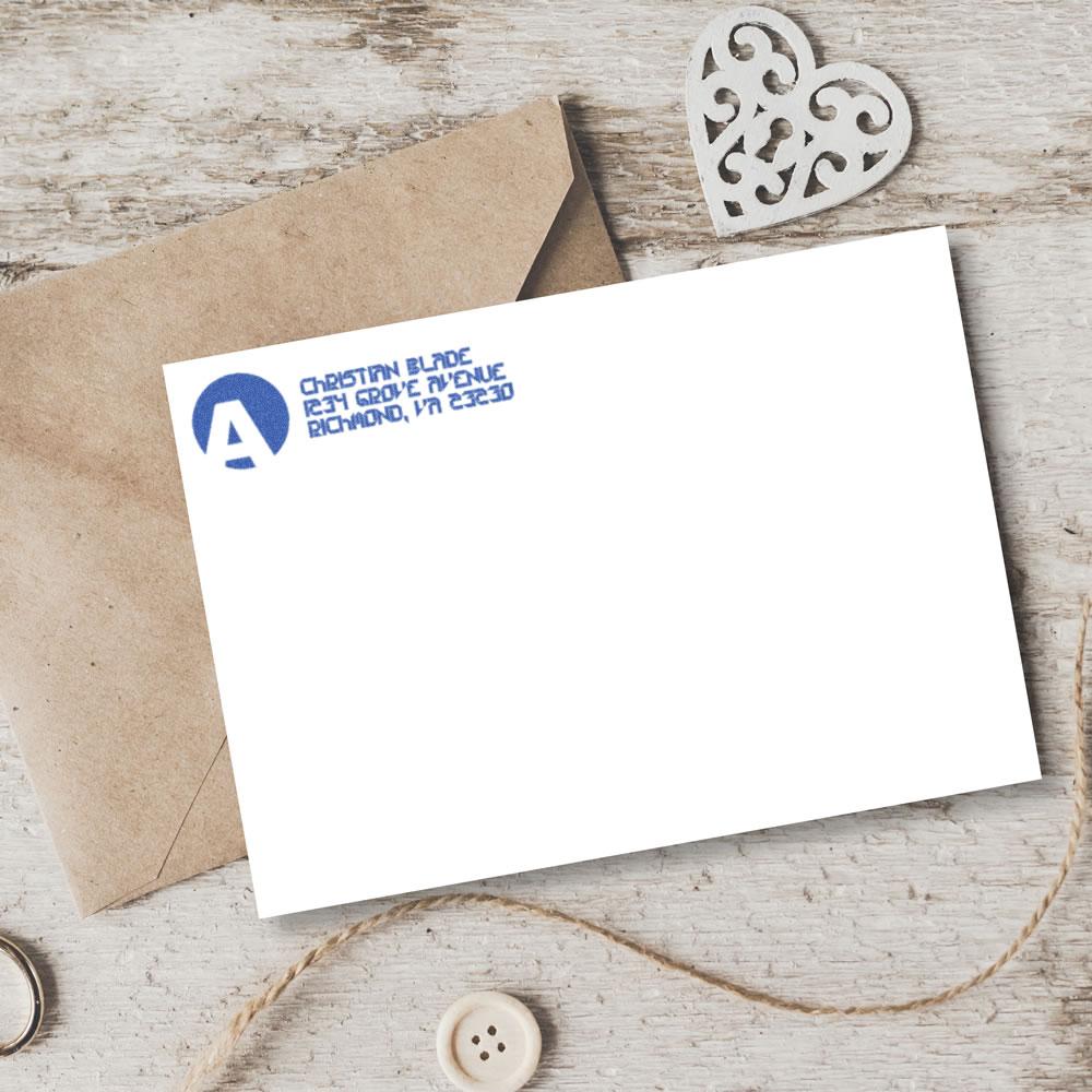 Custom rubber stamp return address imprint on a white card with kraft envelope, showing branded mailing stationery.