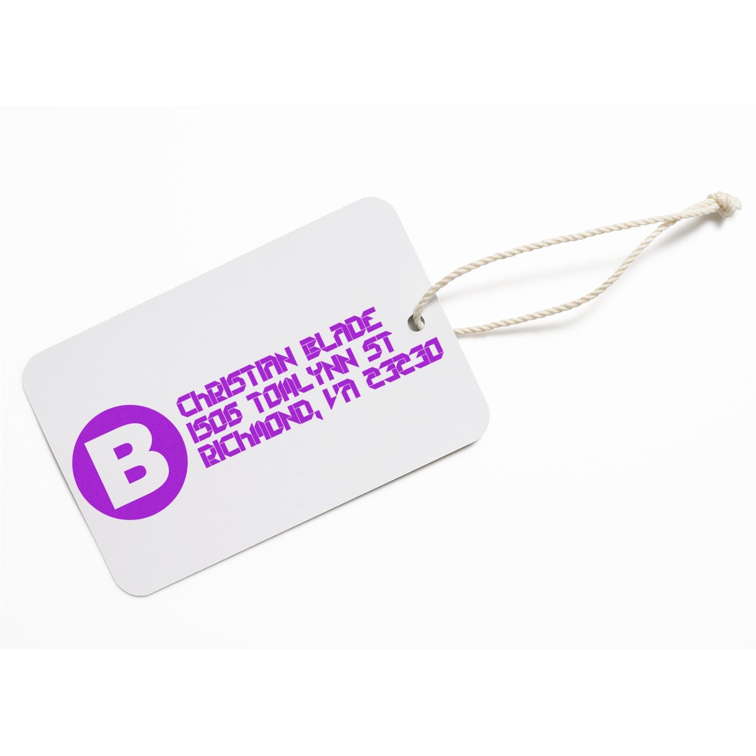 Custom rubber stamp imprint on white clothing tag with purple logo and address for branded apparel labeling.