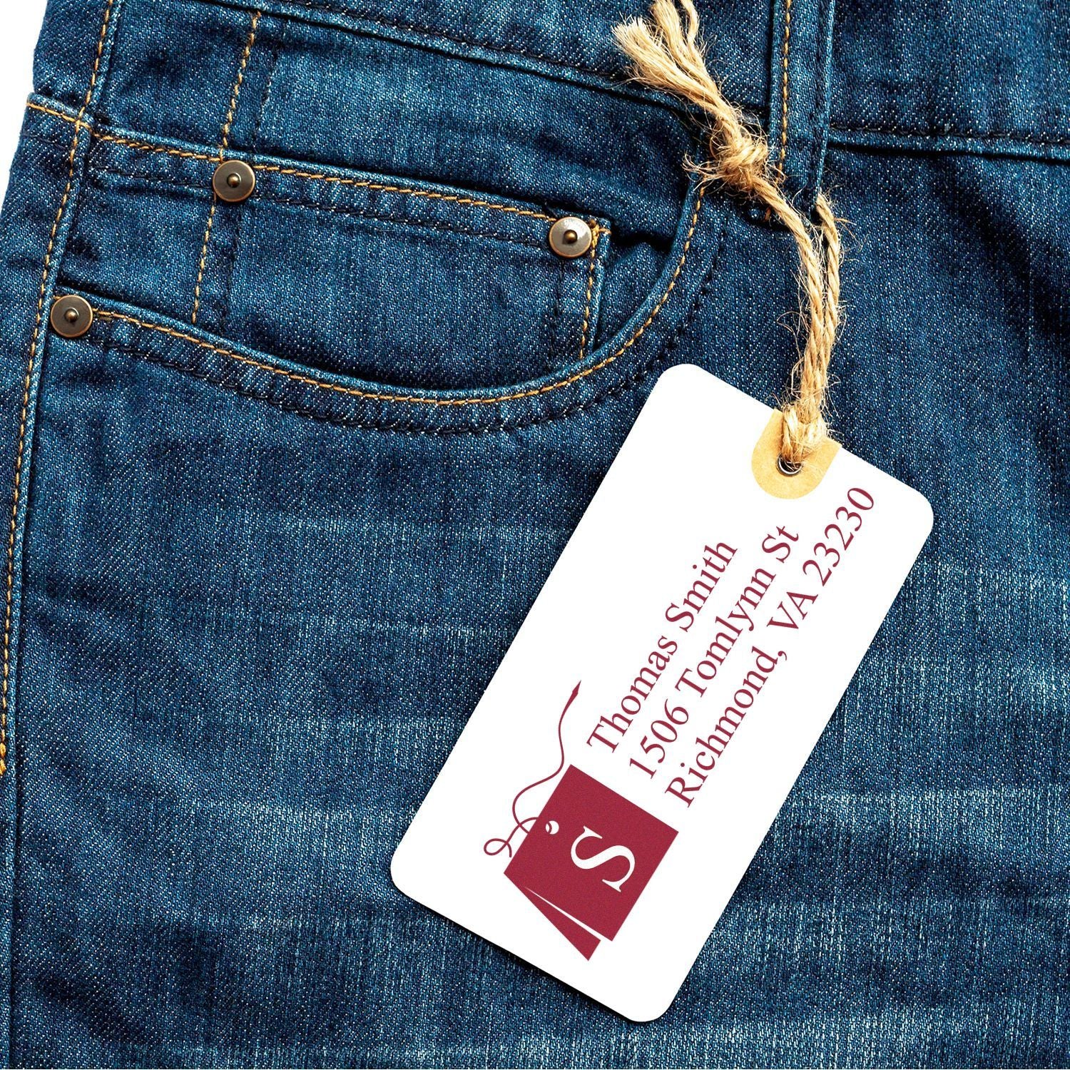 Custom rubber stamp-style clothing tag on denim jeans for apparel branding and return address use.
