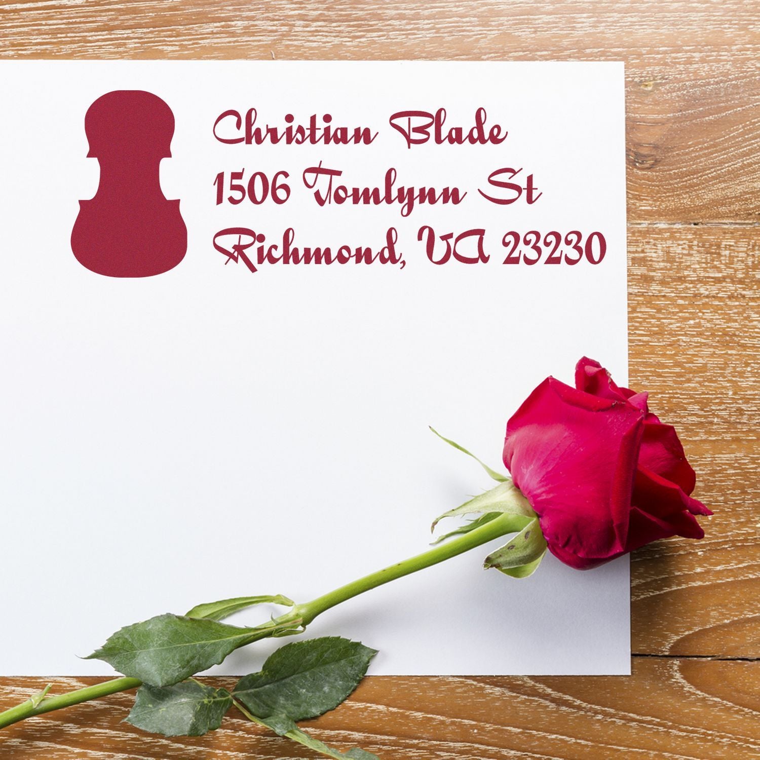 Custom return address rubber stamp with Christian Blade name and Richmond, VA address on a white card beside a red rose.
