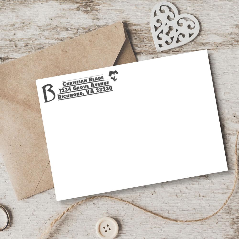 Custom return address rubber stamp on white wedding envelope with kraft paper stationery and heart decor.