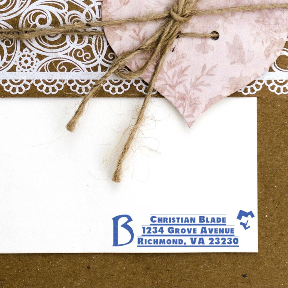 Personalized return address rubber stamp in blue ink on a white envelope for custom stationery and wedding invitations.