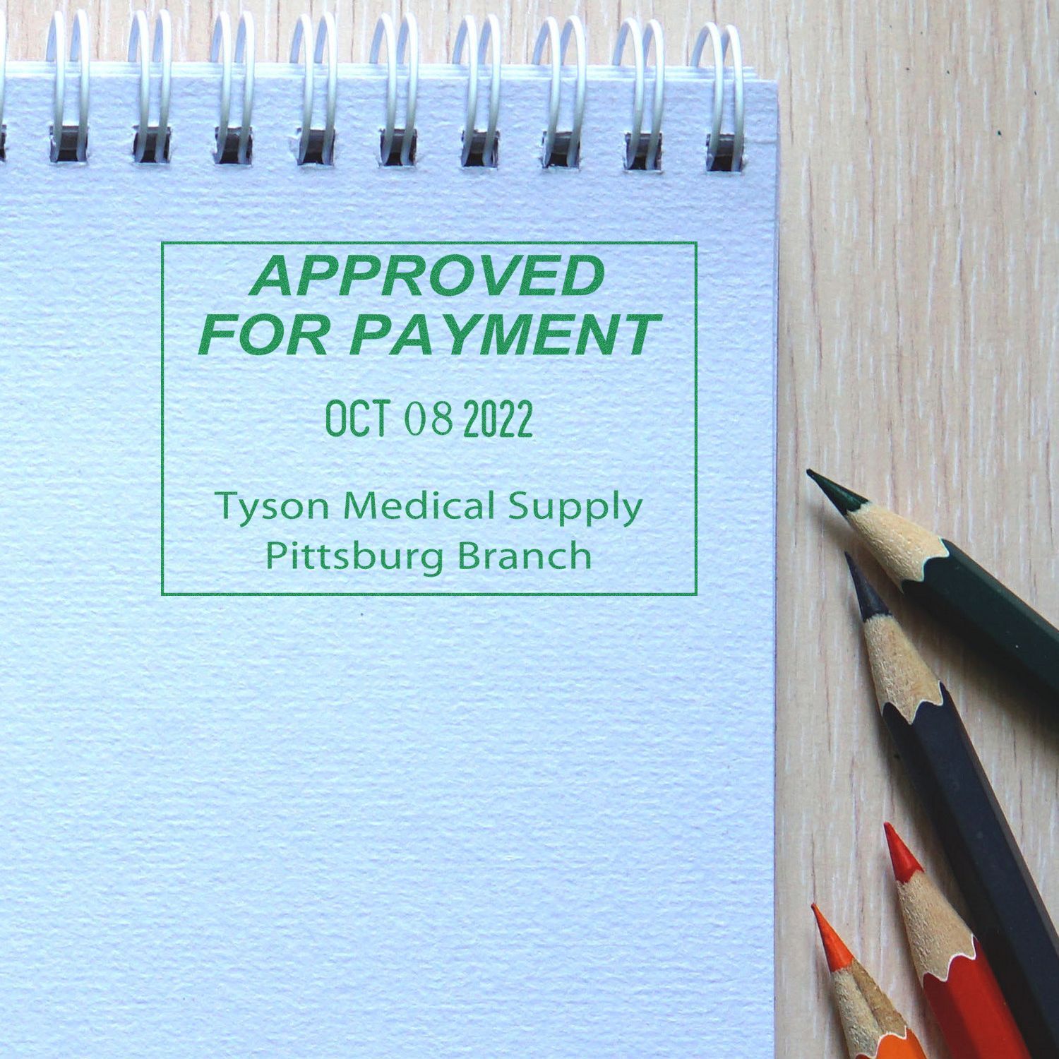 Approved for payment stamp on spiral notebook beside colored pencils, Tyson Medical Supply branch.