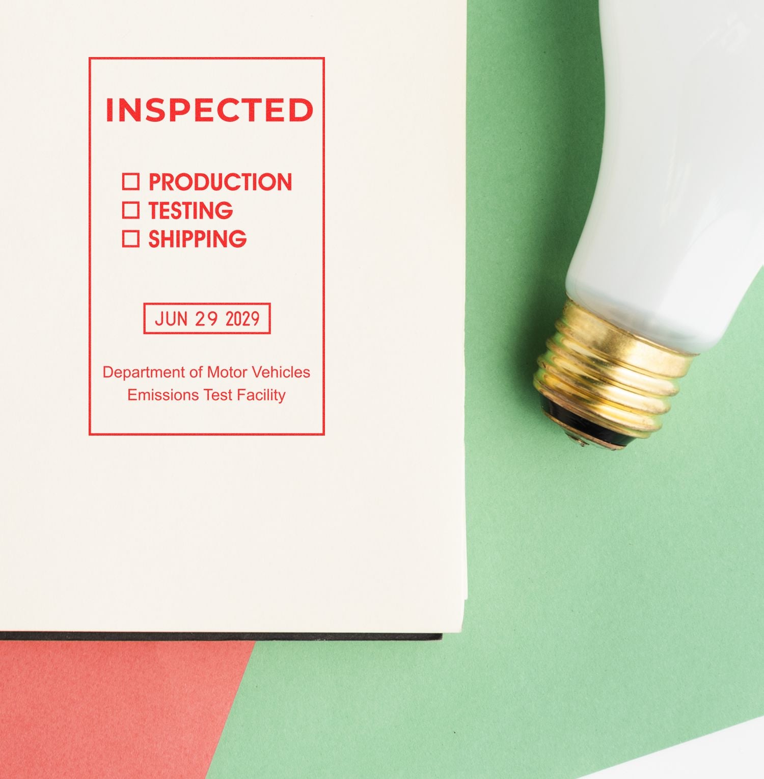 Inspected emissions test sticker beside a light bulb on colorful paper background.