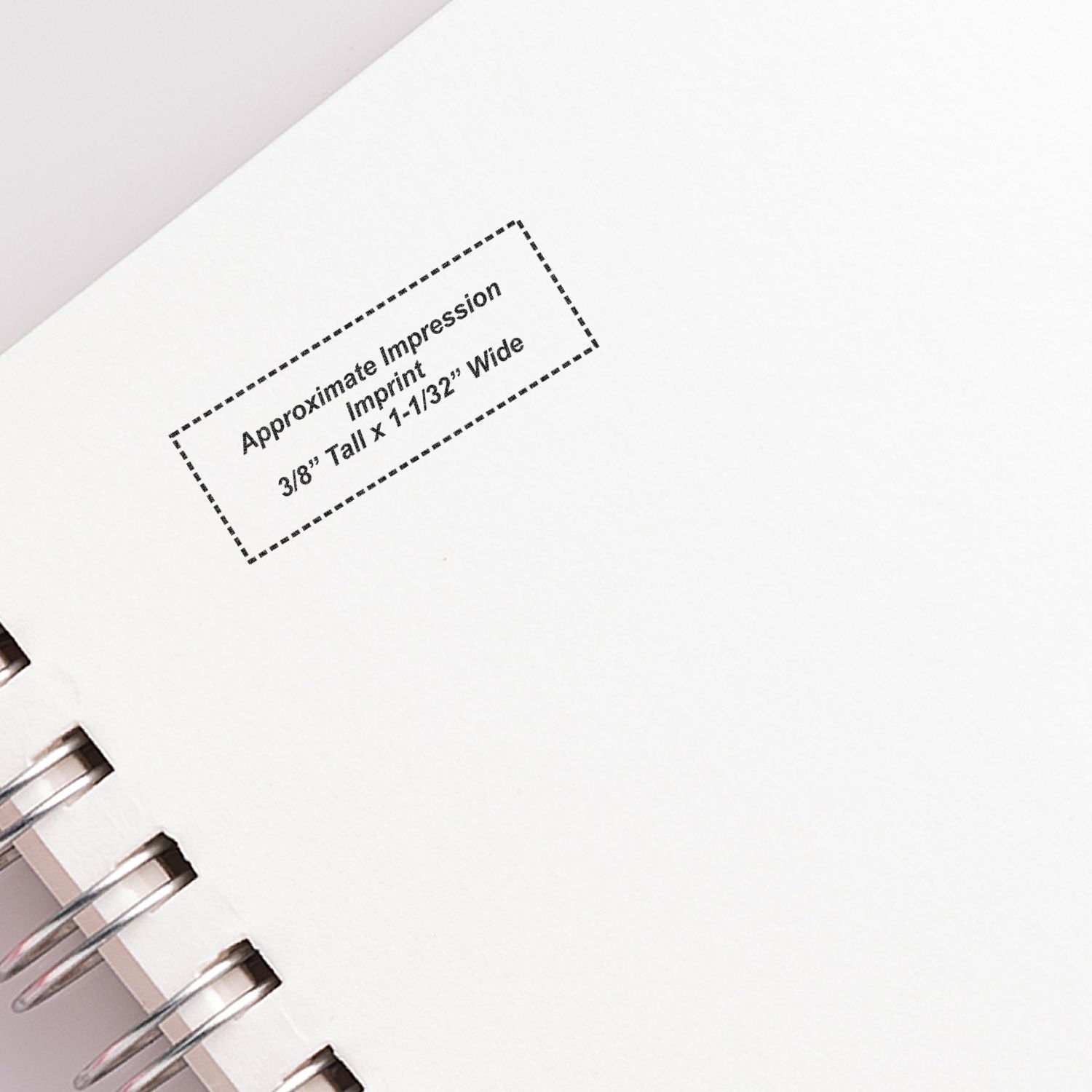 Close-up of a spiral-bound notebook page with printed approximate impression size imprint on white paper.