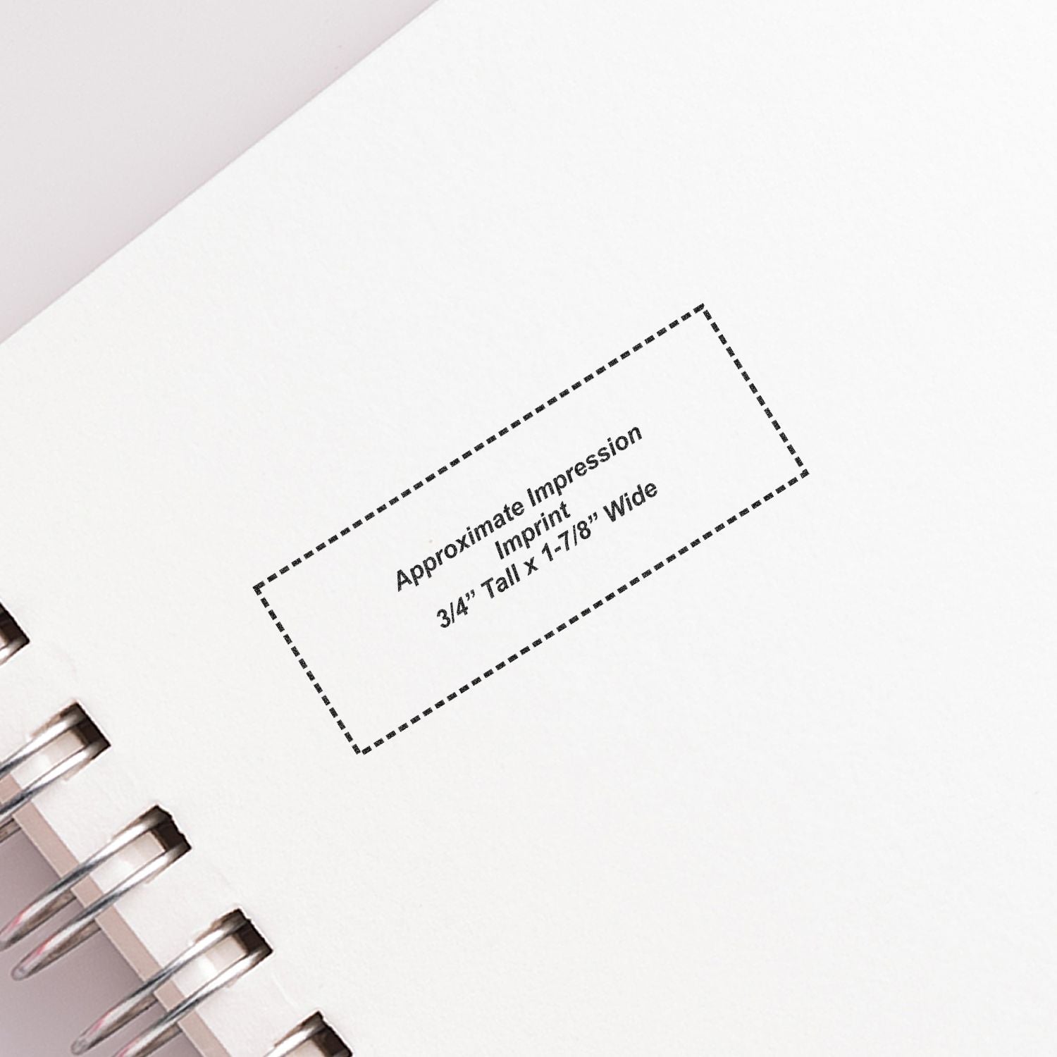 Close-up of spiral-bound notebook page showing an imprint size guide with dashed rectangle and approximate impression dimensions.