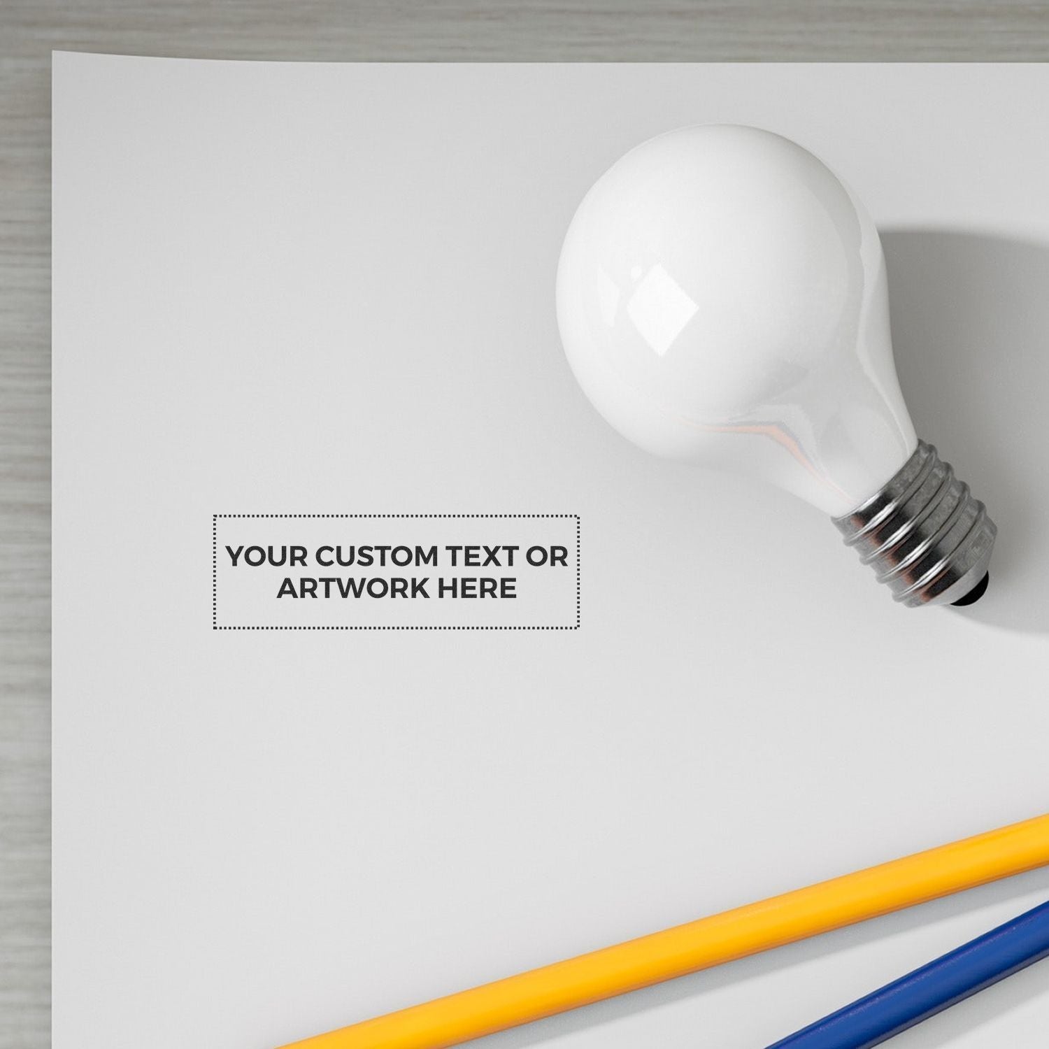 White light bulb mockup with blank custom text area and colored pencils on a clean desk background.