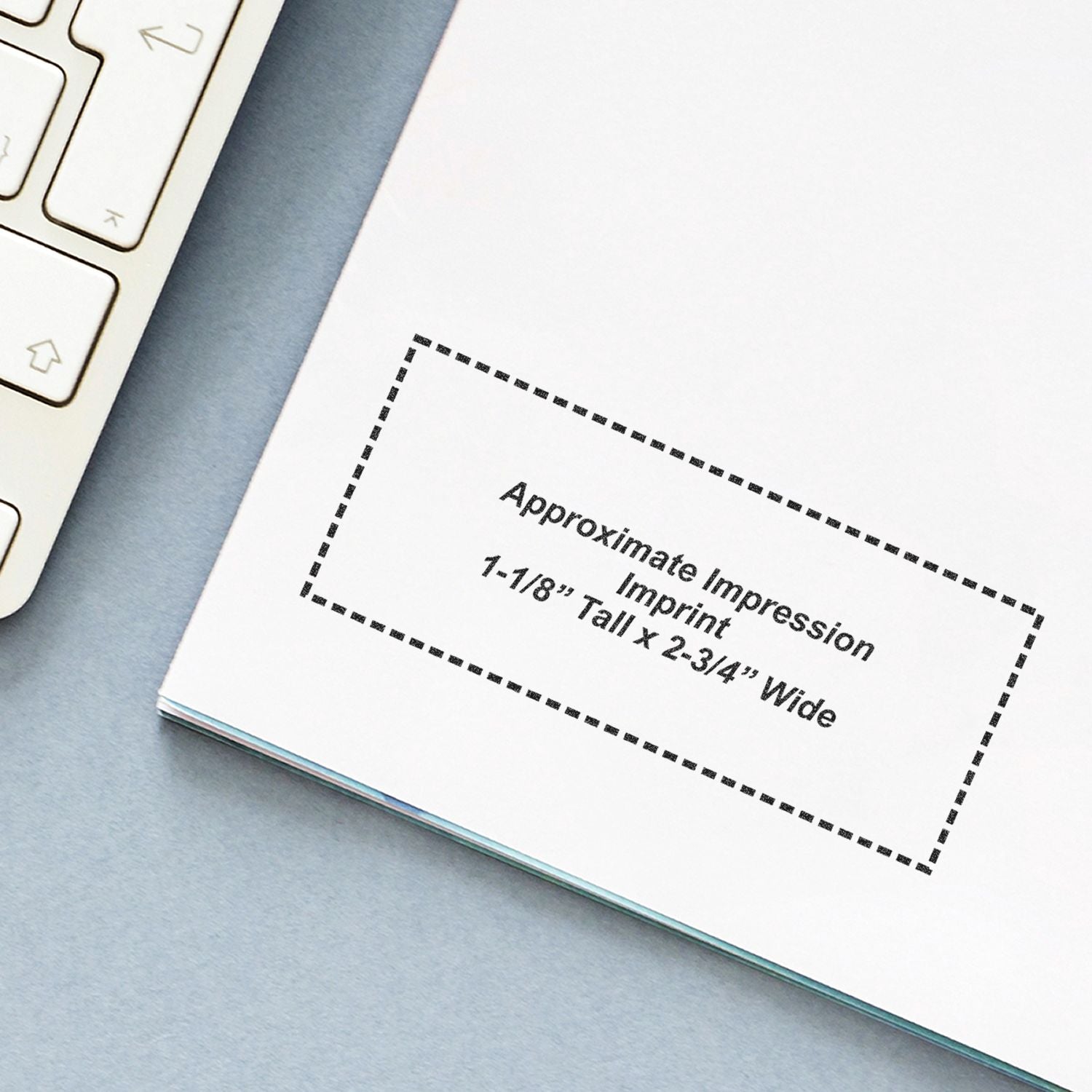 Close-up of laptop keyboard and notebook page showing an approximate impression imprint template, 1-1/8 inch tall by 2-3/4 inch wide.