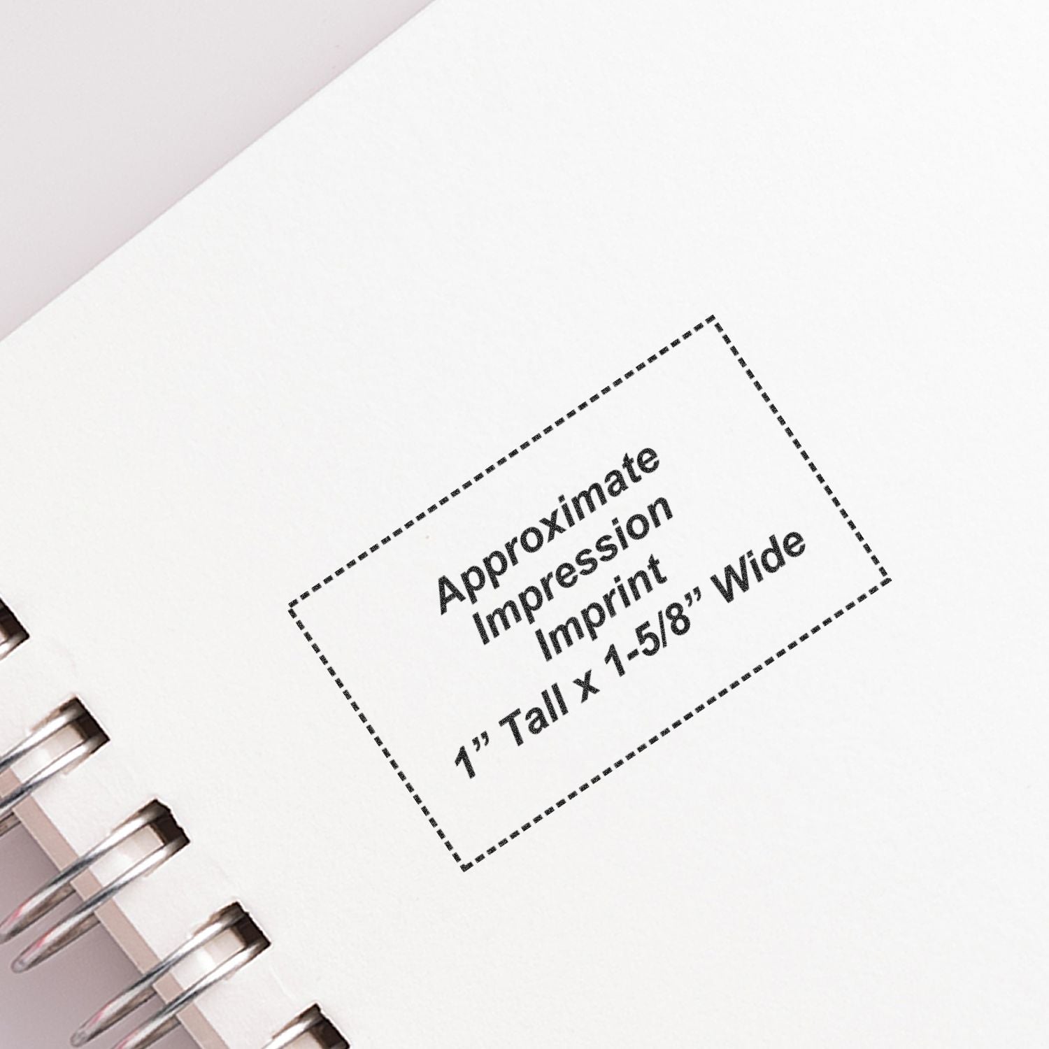 Close-up of a spiral notebook page showing an approximate custom imprint area, 1" tall by 1-5/8" wide.