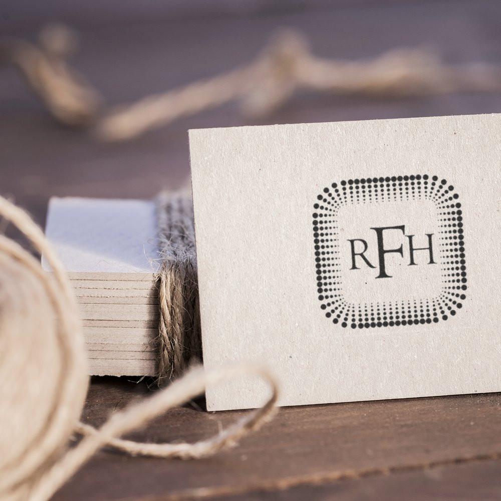 Custom rubber stamp monogram logo on cream paper card with twine, showcasing personalized branding for packaging.