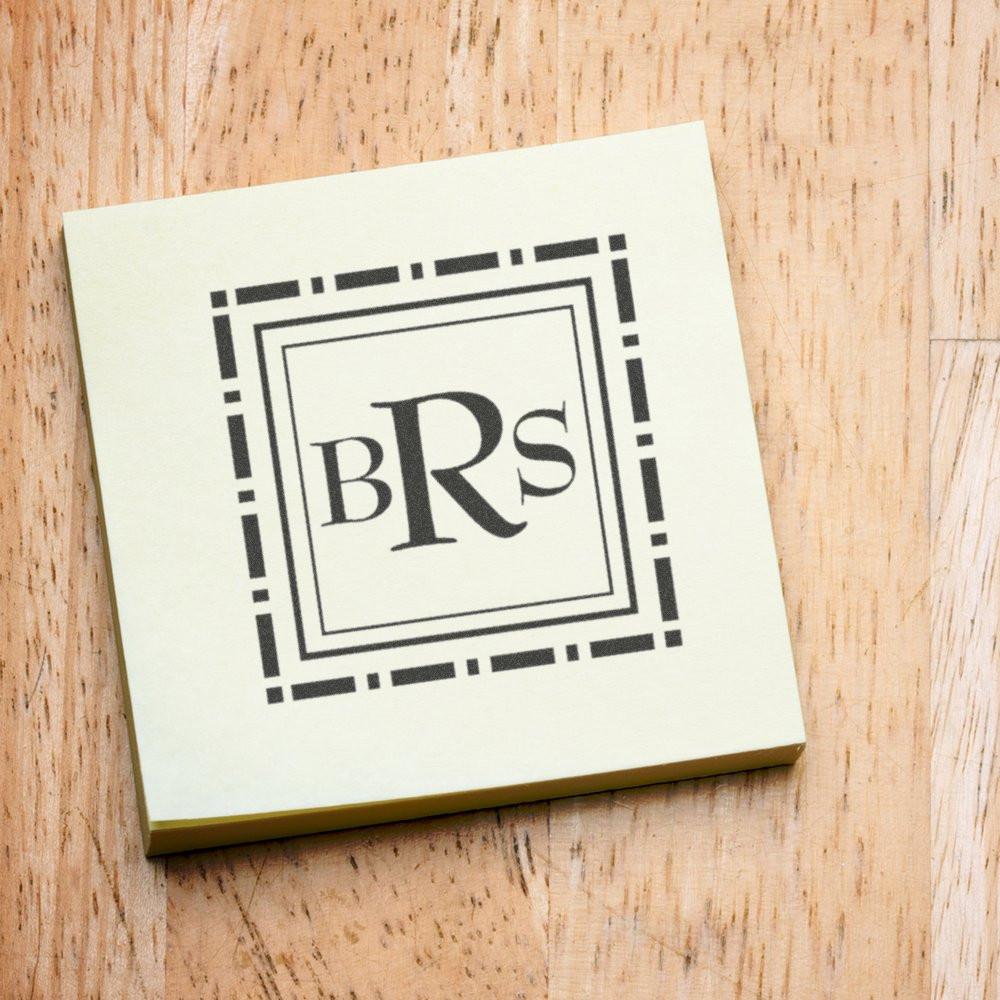 Custom monogram rubber stamp with BRS in a decorative square frame on cardstock, shown on a wood background.
