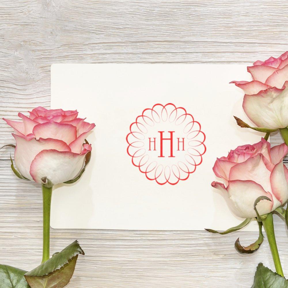 Custom monogram rubber stamp with floral H design on white card, framed by pink roses for elegant wedding stationery.