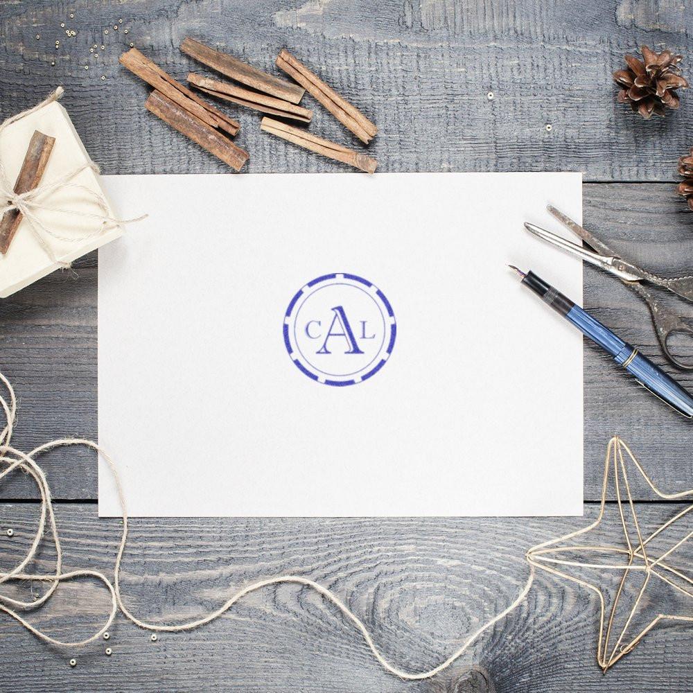Brand logo seal on blank stationery card with blue CA emblem, styled on rustic wooden desk for corporate identity design mockup.