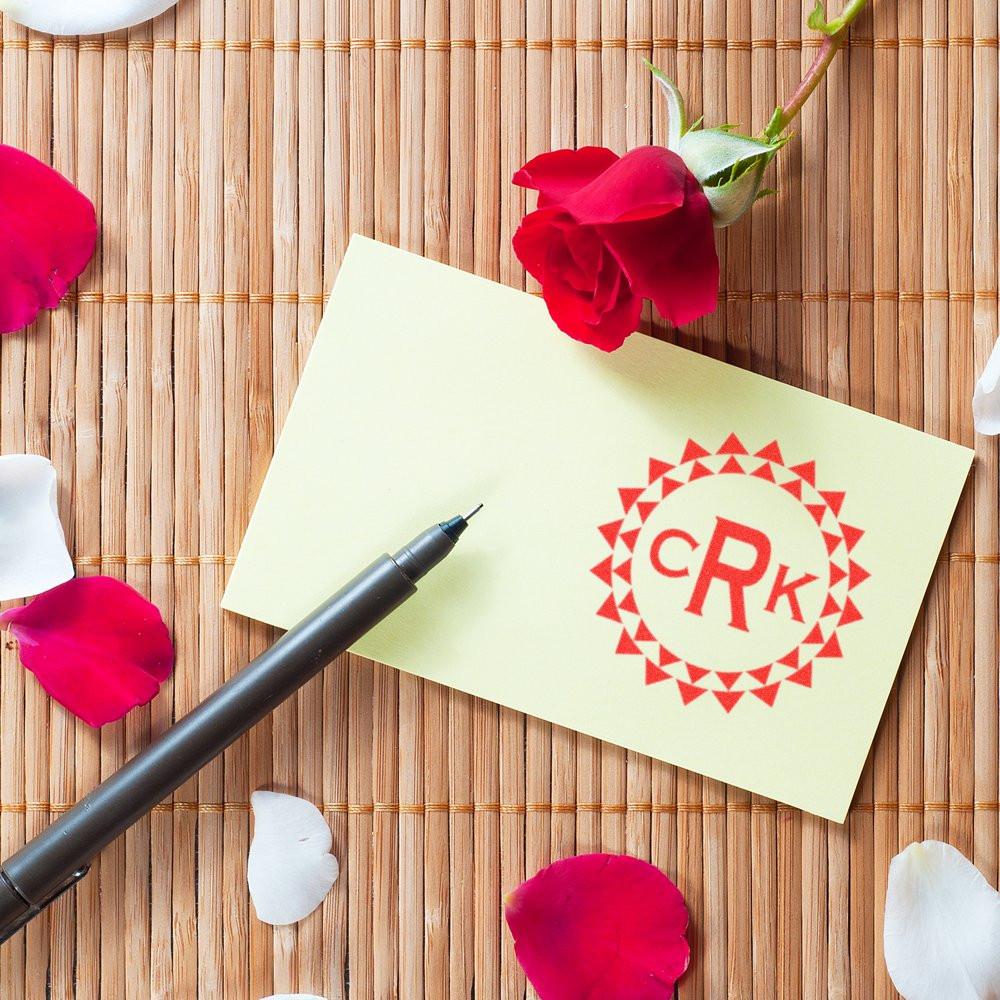 Custom rubber stamp with monogram logo on a card, styled with pen and rose petals for elegant personalized branding.