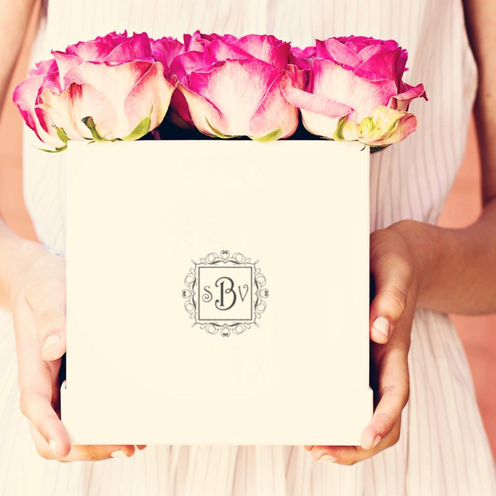 Custom monogram rubber stamp on a wedding gift box with pink roses, ideal for elegant bridal packaging.
