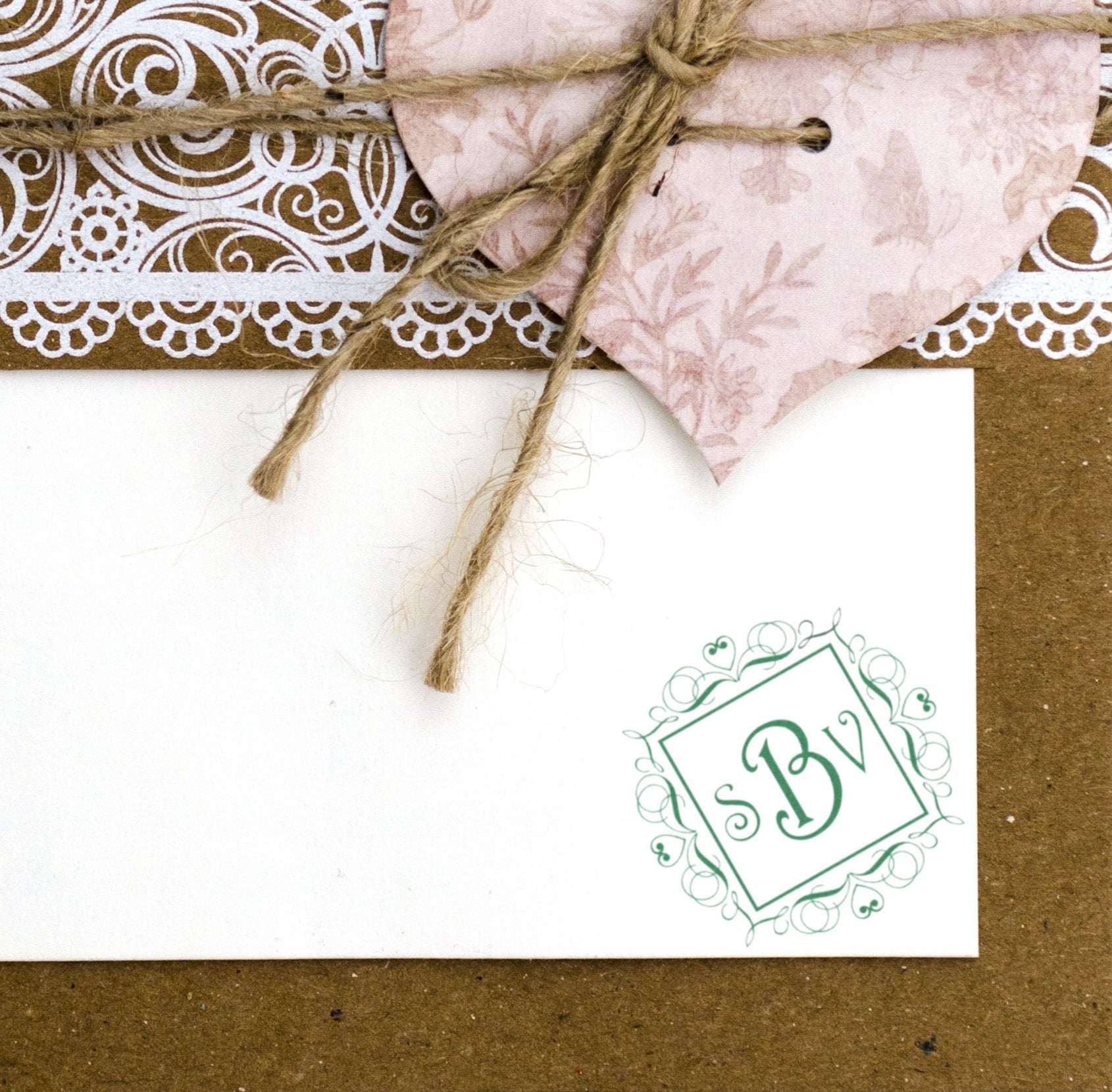Personalized monogram rubber stamp on rustic wedding invitation envelope with twine and lace accents