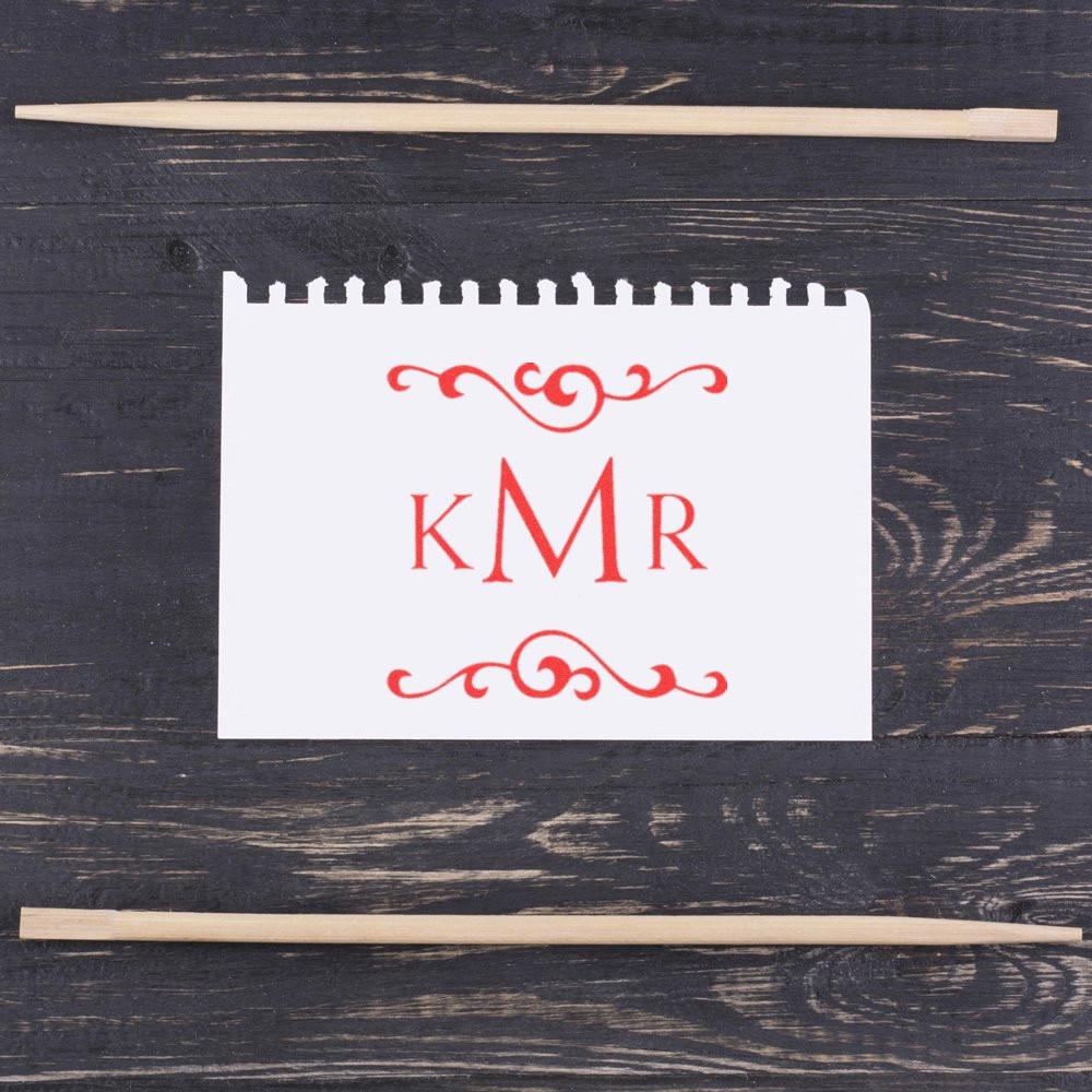 Custom monogram rubber stamp impression with decorative red KMR initials on white card, shown with wooden handles.