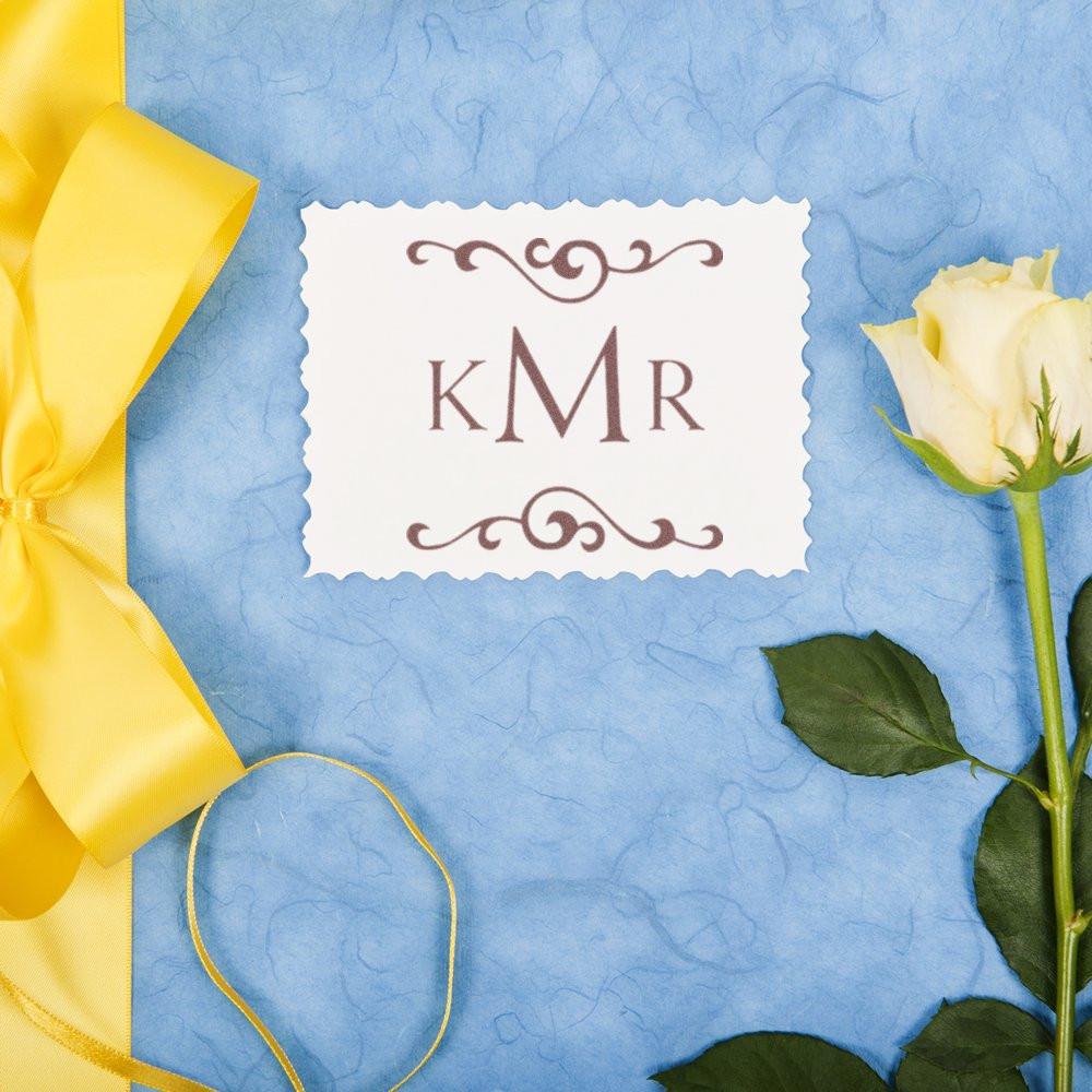 Personalized monogram rubber stamp with KMR design for wedding invitations, styled with ribbon and rose.