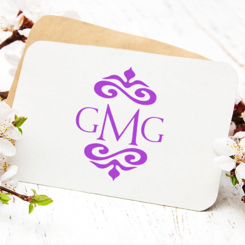 Custom monogram rubber stamp with purple GMG initials and ornate flourishes for wedding stationery