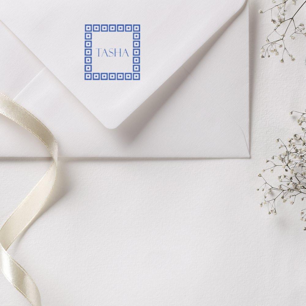 Custom rubber stamp with name Tasha on a white wedding envelope, styled with ribbon and baby's breath.