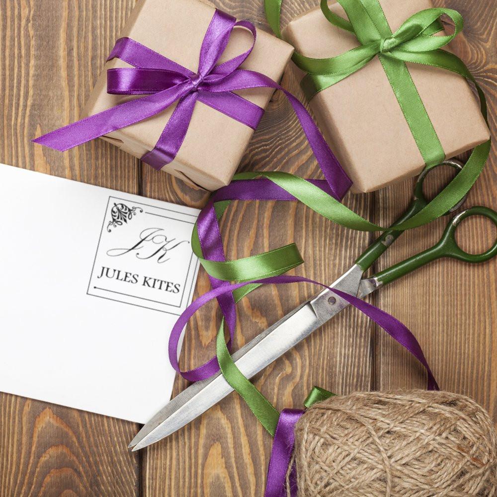 Custom rubber stamp branding on gift packaging with ribbon, scissors, and wrapped presents for small business stationery.